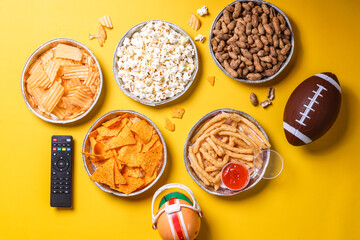 Top view of snacks for watching a football game over yellow background. Super bowl concept.
