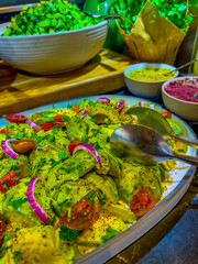 salad of avocado, onion, tomato and parsley seasoned with herbs and light dressing. on large platter surrounded by salads and condiments. catering event on festive event, party or wedding reception