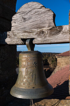 Vista de una campana antigua de bronce con su yugo en un campanario de la españa vaciada.