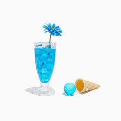 Transparent blue cocktail with flower, waffle ice cream cone and blue glass sphere. Abstract summer drink, party scene. Trendy minimalist drink composition.