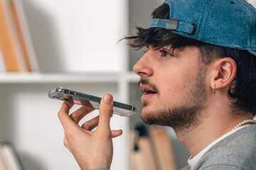 young man with cap and phone sending voice message