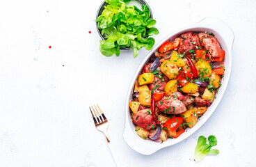 Baked spicy turkey ragout with potatoes, paprika, red onion, herbs and spices in oval ceramic baking dish, white table background, top view, copy space