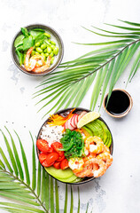Poke bowl with shrimp, avocado, radish, carrot, tomato, seaweed and white rice. White table background, top view