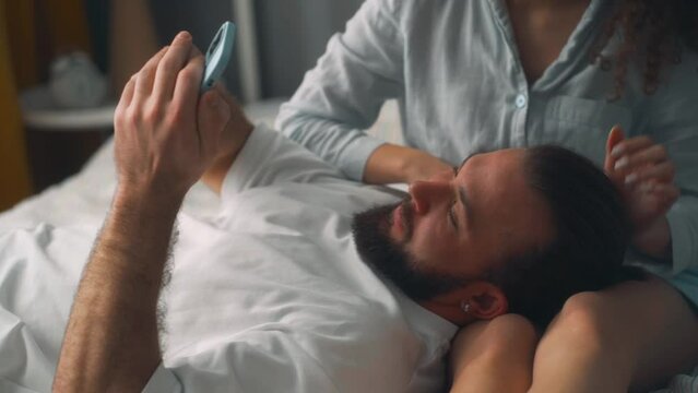 Cheerful romantic couple taking a selfie with a smartphone in bedroom Man and woman using cell phone to take pictures in bed. family making video call, talking chatting slow motion