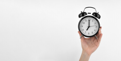Isolated woman's hand holds a black alarm clock