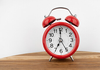Red alarm clock on grey wall background