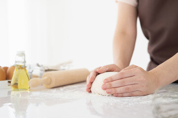 Obraz na płótnie Canvas Female hands kneading dough, baking background. Cooking ingredients eggs, flour, milk, rolling pin on white style kitchen. Copy space.