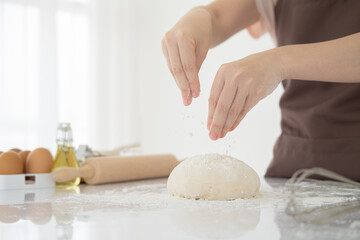 Close-up Female hands kneading dough on sprinkled with flour on white table .Copy space.