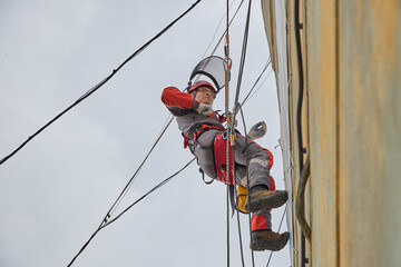 Rope access is a high-risk job. A man works on ropes.