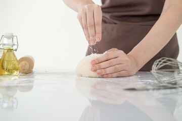 Obraz na płótnie Canvas Close-up Female hands kneading dough on sprinkled with flour on white table .Copy space.