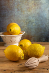 close up of lemons in drainer on rustic table with wooden squeezer, selective focus, vertical, with copy space