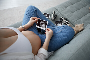 Pregnant woman sitting hold ultrasound photo of belly strokes tummy fetus abdomen enjoying...