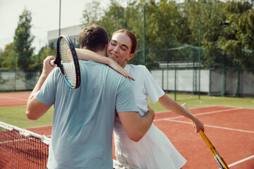 Happy couple, two tennis player embrace after a winning game. Active leisure game. Weekend activity...
