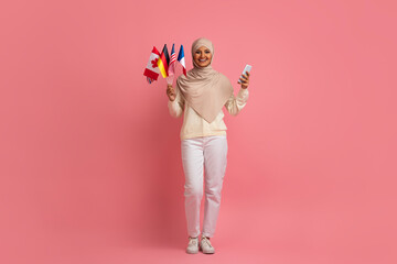 Portrait Of Happy Muslim Woman Holding Bunch Of International Flags And Smartphone