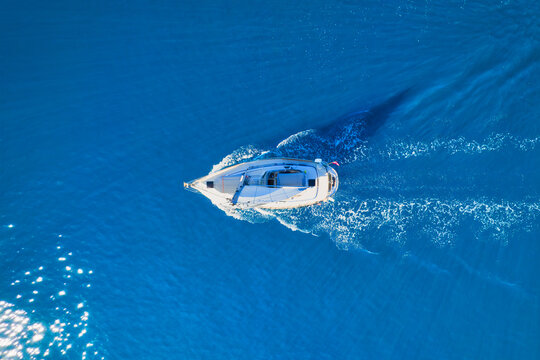 Wave and sail yacht on the sea as a background. .Sea and waves from top view. Blue water background from top view. Top view from drone. Summertime vacation. Travel image