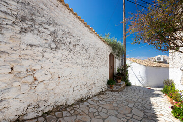Ulice śródziemnomorskiej wioski na wyspie Korfu w Grecji. Biała architektura w starym mieście Afionas. Niebieskie niebo. © anettastar