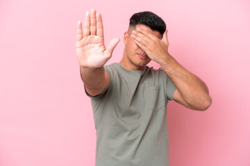 Young caucasian handsome man isolated on pink background making stop gesture and covering face