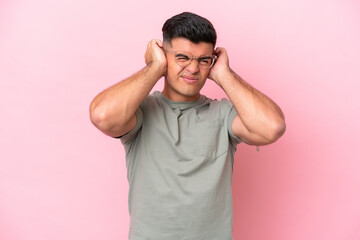 Young caucasian handsome man isolated on pink background frustrated and covering ears