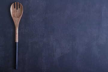Wooden spoon with black handle on a blue dark background. Copy space. Top view