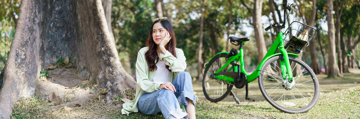 Fototapeta na wymiar Women sitting under tree with serene happiness and watching view to resting after cycling in park