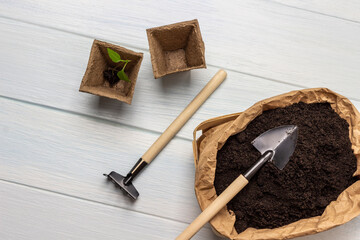 Soil in a paper bag and a shovel on top. Rakes and peat pots.