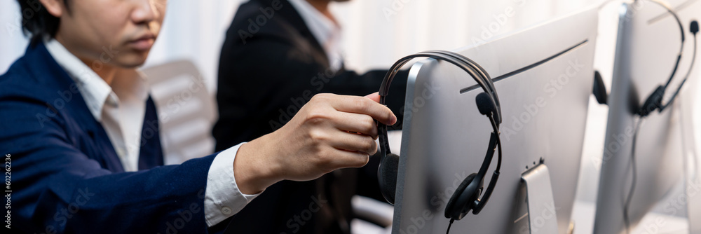 Aufkleber panorama focus hand holding headset on call center workspace desk with blur background of operator t