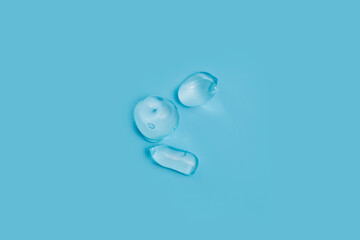An extruded transparent gel, as a sample of a cosmetic product, on a blue background. Top view, flat lay