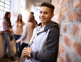 Education, happy and portrait of man in college hallway for studying, learning and scholarship. Future, smile and knowledge with student leaning on brick wall for university, academy and campus