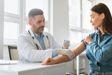 Fototapeta premium Protecting your health. Young woman getting vaccine shot against viruses, male doctor giving injection to female patient