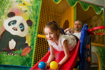 a happy girl with her father rides a roller coaster at the children's play center
