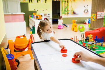 a little girl is playing at the children's creative center, playing air hockey