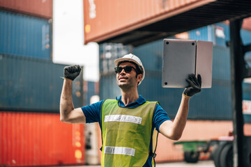 Engineer dock worker in protective safety jumpsuit uniform and with hardhat and use laptop computer at cargo container shipping warehouse. transportation import,export logistic industrial
