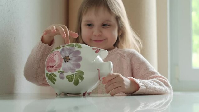 The mother gives her daughter a 1 euro coin, which she decides to save by adding the coin to the piggy bank