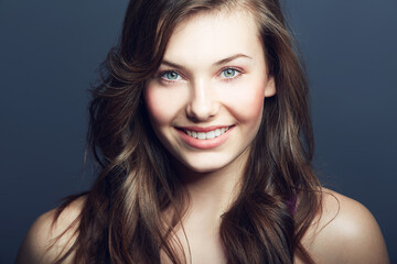 Beauty, natural and portrait of happy woman in studio with makeup, facial and skincare routine. Health, smile and face of young female model with cosmetic or dermatology treatment by blue background.