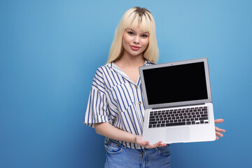 blond caucasian 20s woman manager in striped shirt holding laptop on studio background with copy space