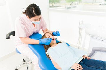 Fototapeta premium Caucasian pediatric dentist treating a young child patient