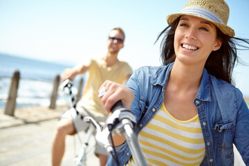 Bike, cycling and couple with a travel woman on summer vacation or holiday riding on the promenade...