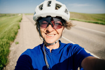 cyclist in a white helmet takes a selfie and smiles