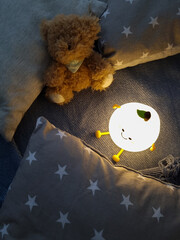 Kids' night light among pillows and toys. Turned on the night light. Cozy shelter for a little toddler. A cute flashlight that illuminates the nursery room.