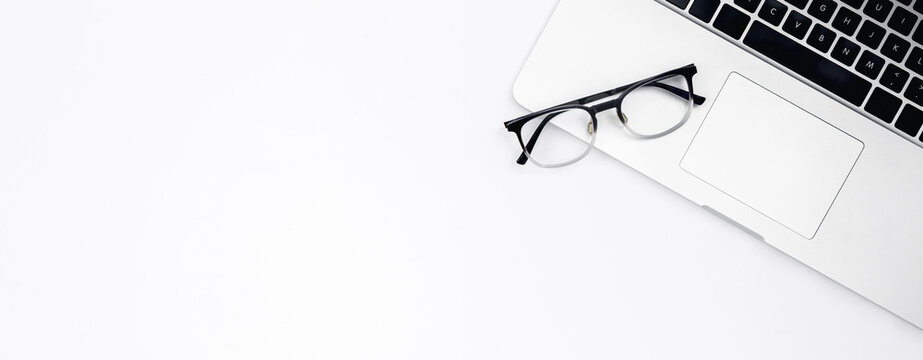 Laptop and glasses on a white background, top view.
