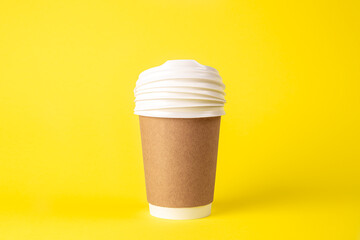 Paper cup and plastic lids on a yellow background isolated.