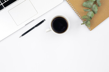 Laptop, notebook and a cup of black coffee on a white background, top view.