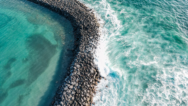 Aerial view of a seawall with clear turquoise water