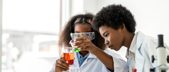 Two african american cute little boy and girl student child learn science research and doing a chemical science experiment making analyzing and mix liquid in test tube on class at school