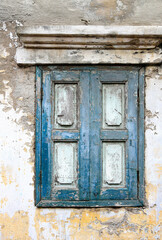 Dusty white ancient building facade with the blue wooden windows.