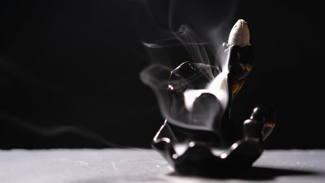 The frankincense rests on a black incense stand with smoke slowly moving.