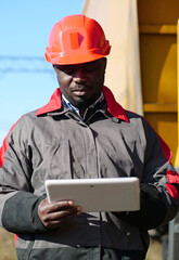 African american railway man with tablet computer at freight train terminal