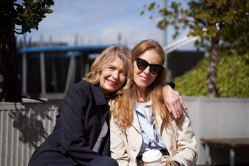 Fototapeta premium Two women looking at the camera and smiling while posing together outdoors.