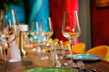 Clear wine glasses on a wooden table in a restaurant.