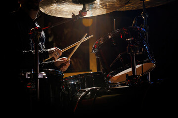 Close-up of drummer drumsticks with a drum set.